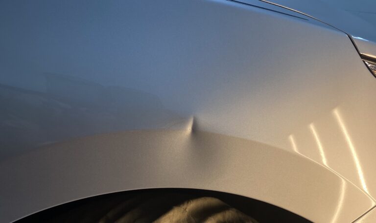 Silver fender dent before paintless dent repair